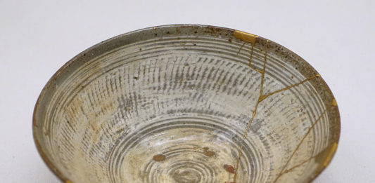Lucrări de reparație (în partea dreaptă) prin metoda kintsugi cu lac auriu pe un bol de ceai de tipul hakeme Mishima, secolul al XVI-lea (Muzeul Etnologic din Berlin). Sursa: Wikipedia