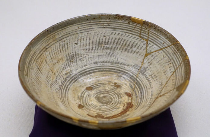 Lucrări de reparație (în partea dreaptă) prin metoda kintsugi cu lac auriu pe un bol de ceai de tipul hakeme Mishima, secolul al XVI-lea (Muzeul Etnologic din Berlin). Sursa: Wikipedia